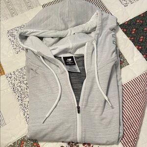 New Balance grey heather 1/4 zip top with NB logo on hood and longer length back